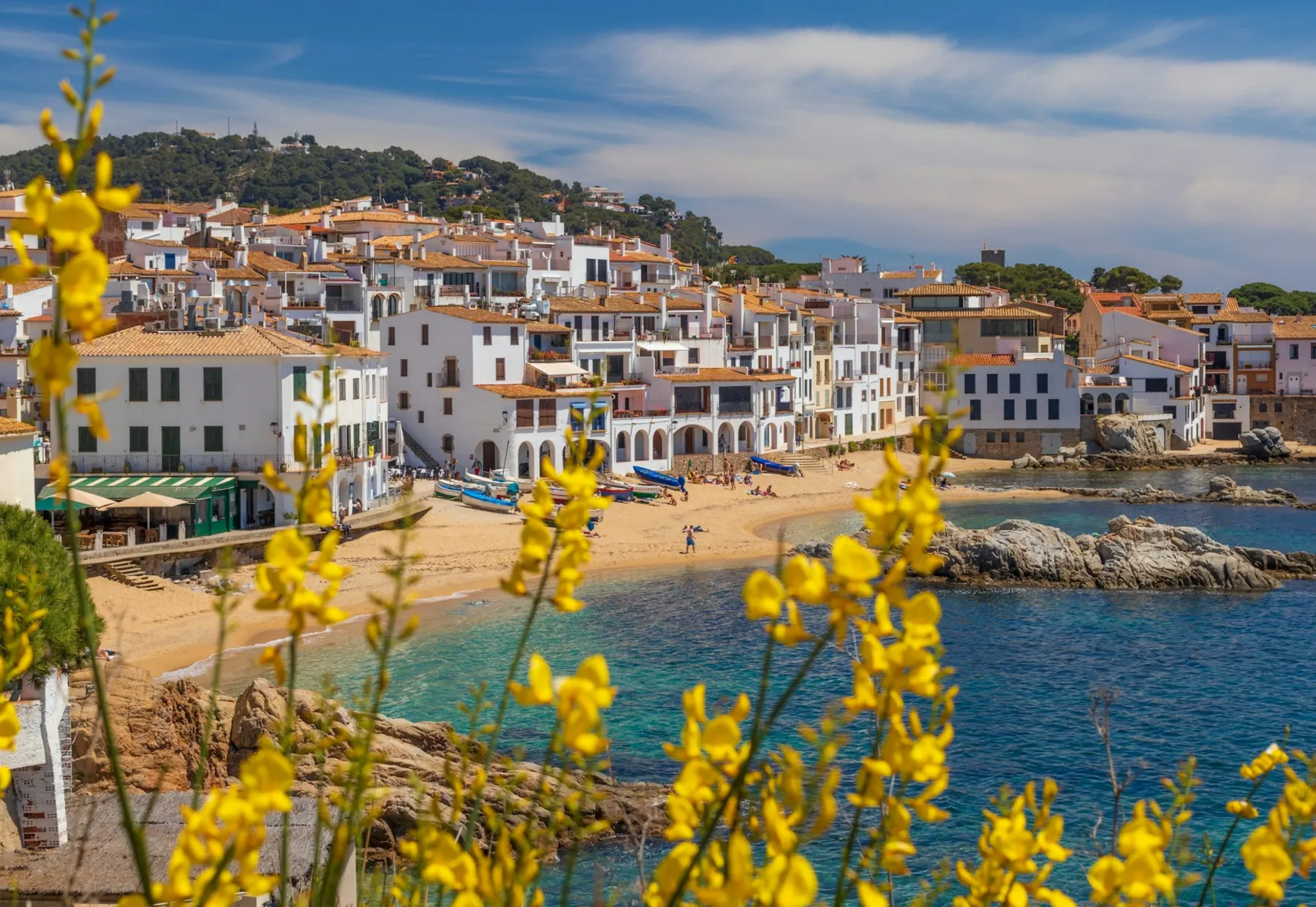 White Mediterranean village houses beside a sandy beach and turquoise coastal water