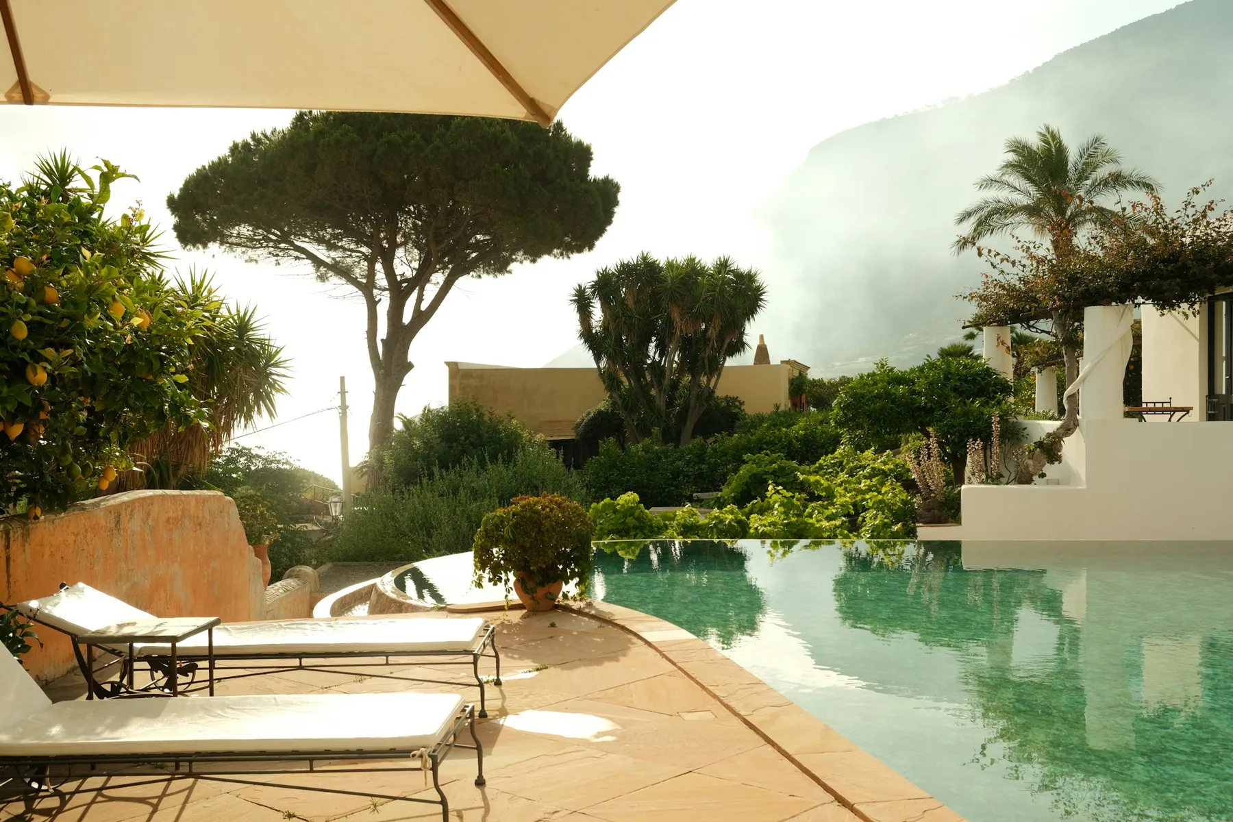 A landscaped resort pool with sun loungers and Mediterranean gardens
